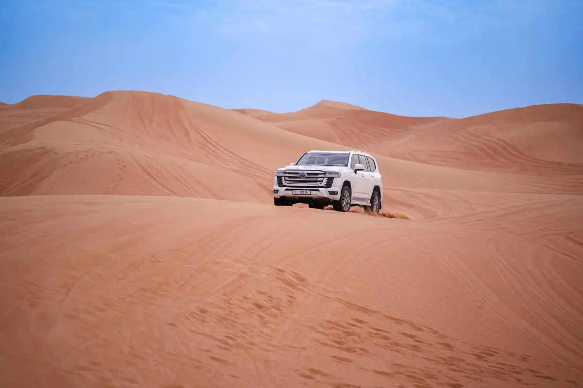 white Toyota 4x4 on sand dunes in desert