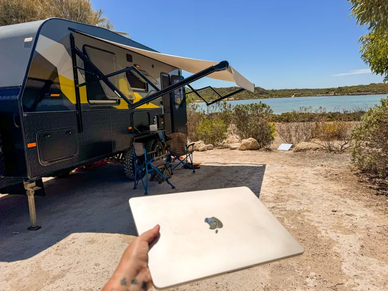 laptop remote worker with campsite view in caravan