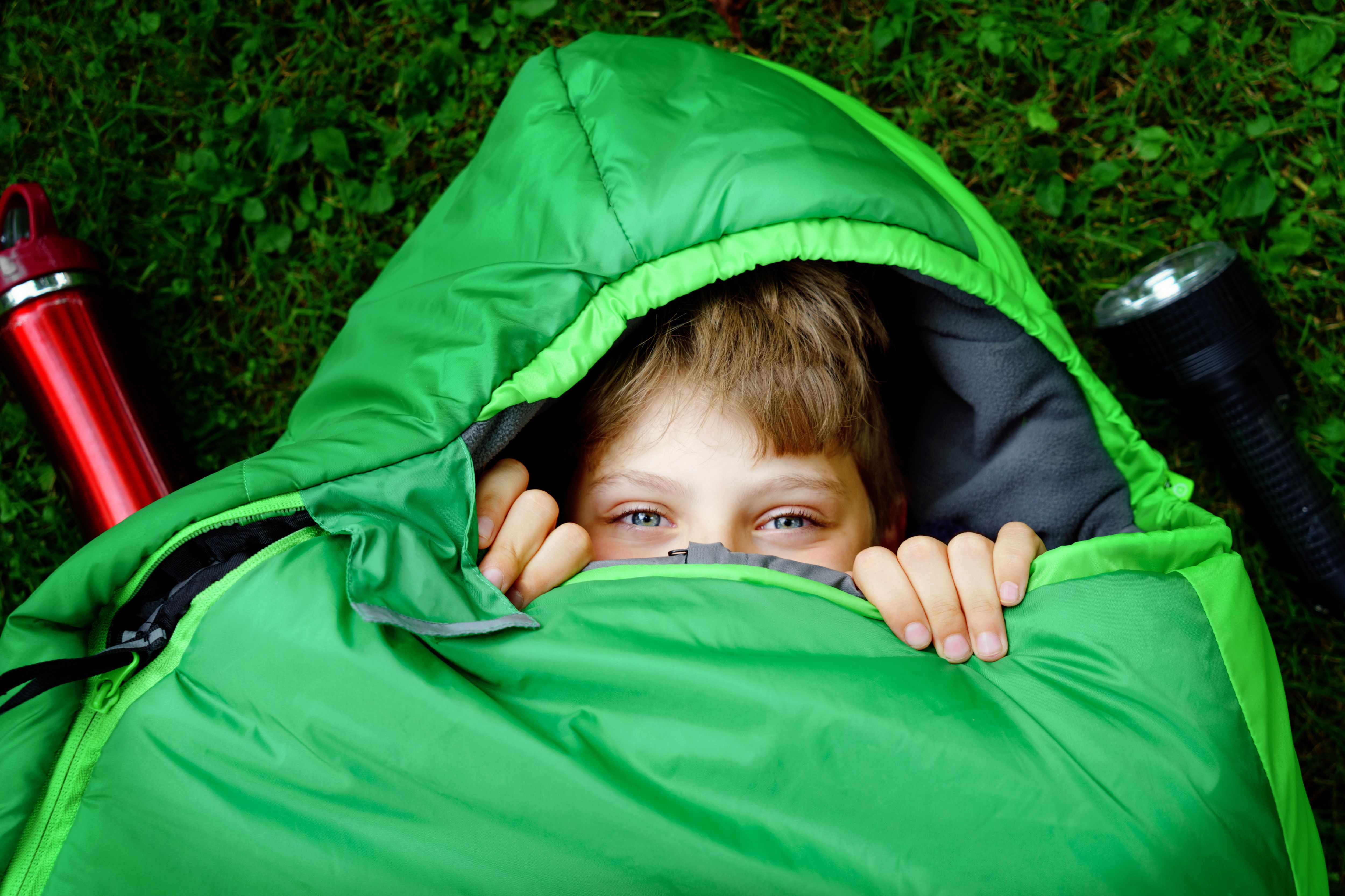 A kid in a sleeping bag, his head peeking out