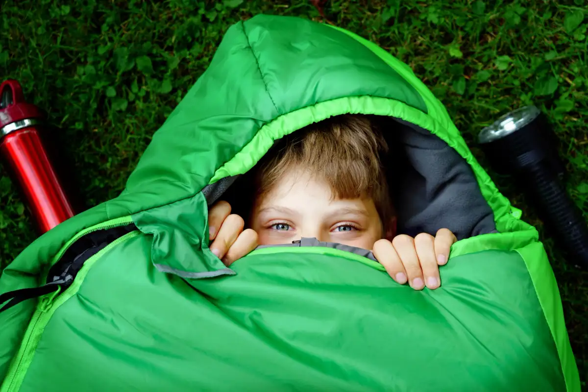 A kid in a sleeping bag, his head peeking out