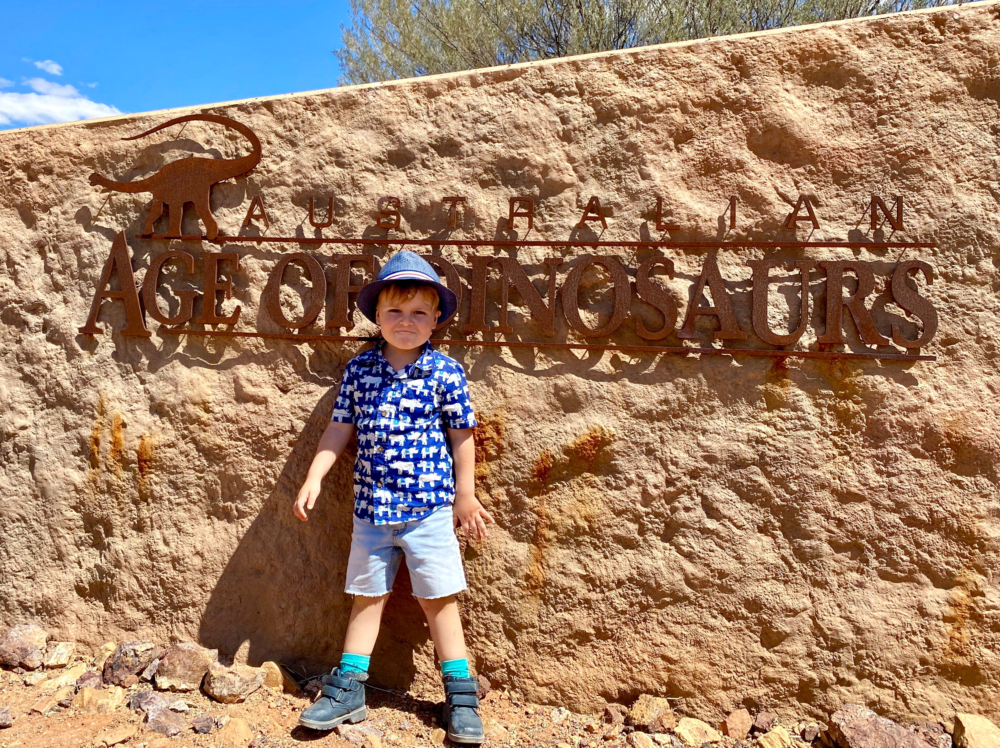 A child photographed in front of an age of dinosaurs sign in Winton, QLD