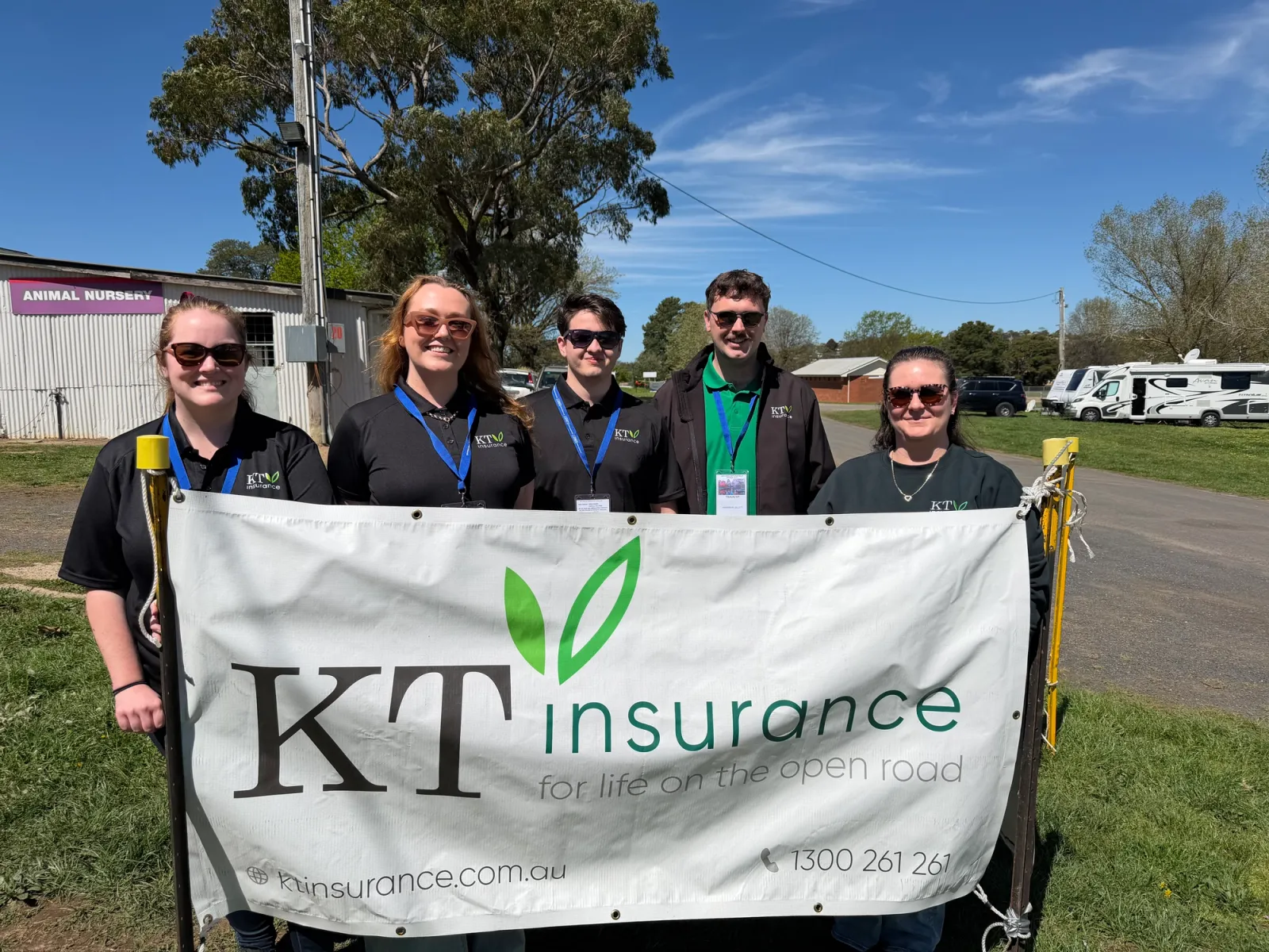 five people stood behind a banner on a sunny day