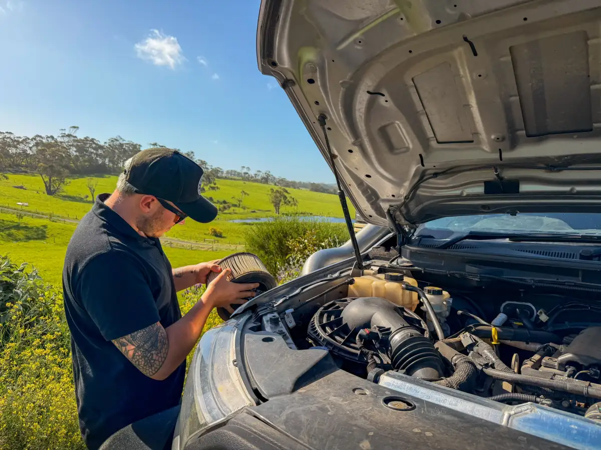 man checking the engine bay of a 4wd and inspecting the air filter