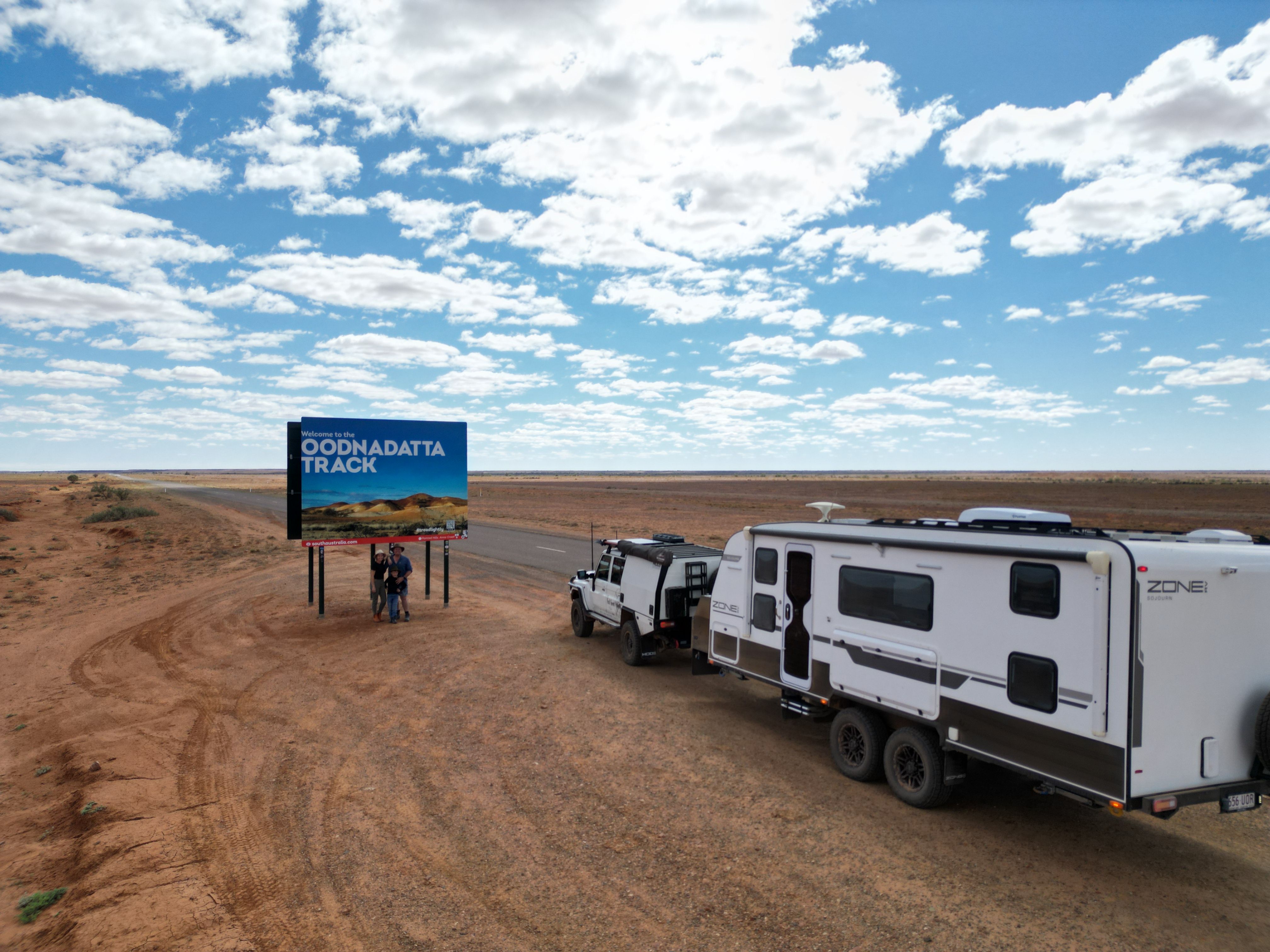 4x4 and caravan posed with road sign in desert