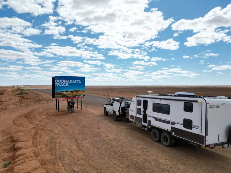 4x4 and caravan posed with road sign in desert