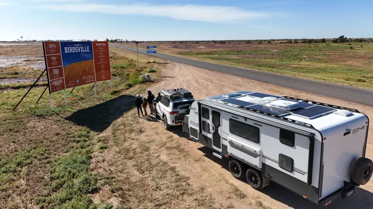 4x4 towing caravan on side of highway with road sign