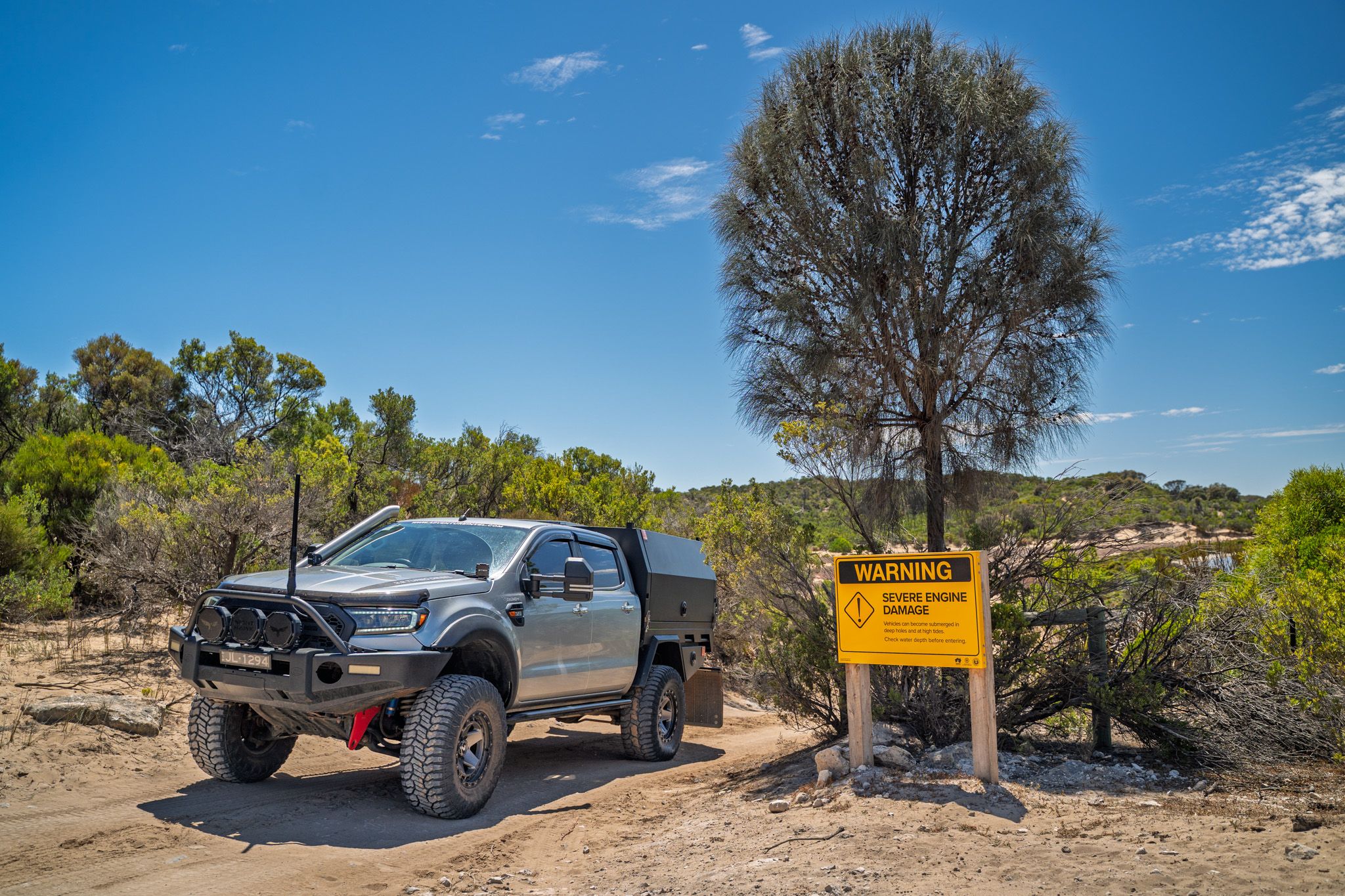 a 4X4 Ford Ranger next to a road sign reading "Warning: Severe Engine Damage"