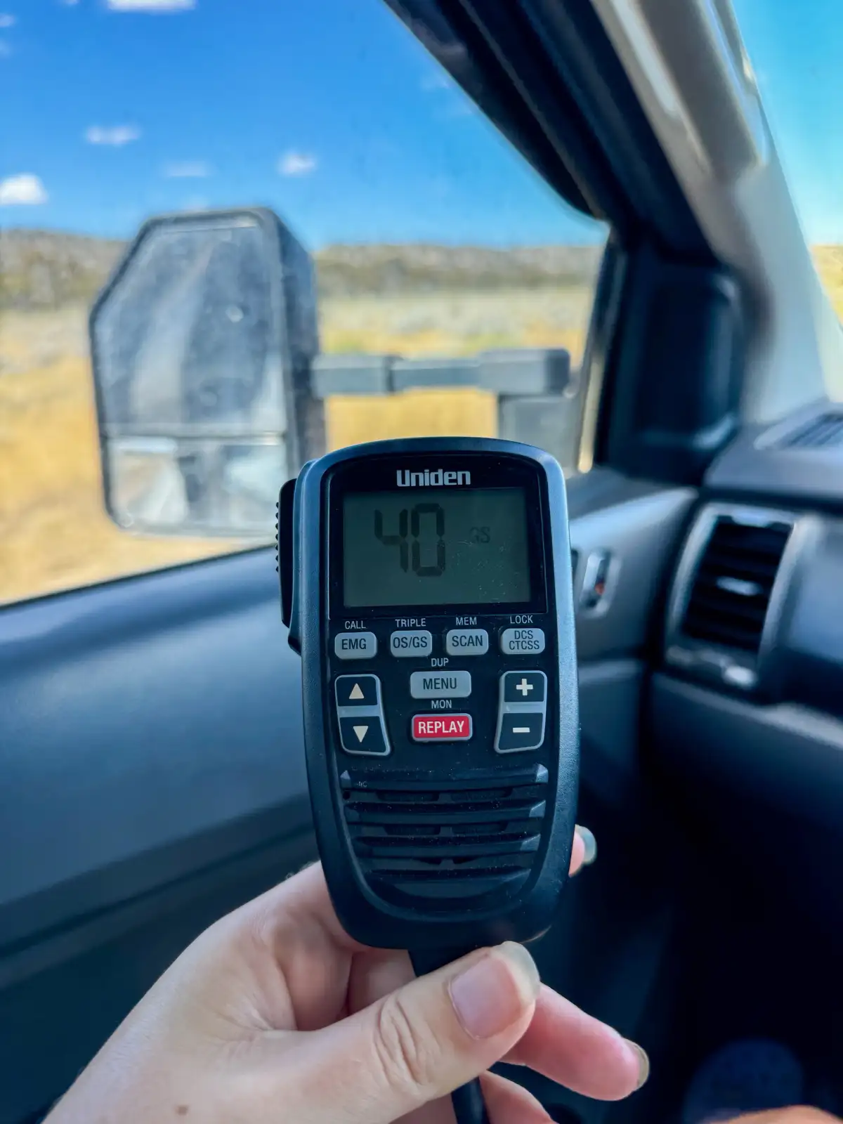 a UHF radio in someone's hand in a car