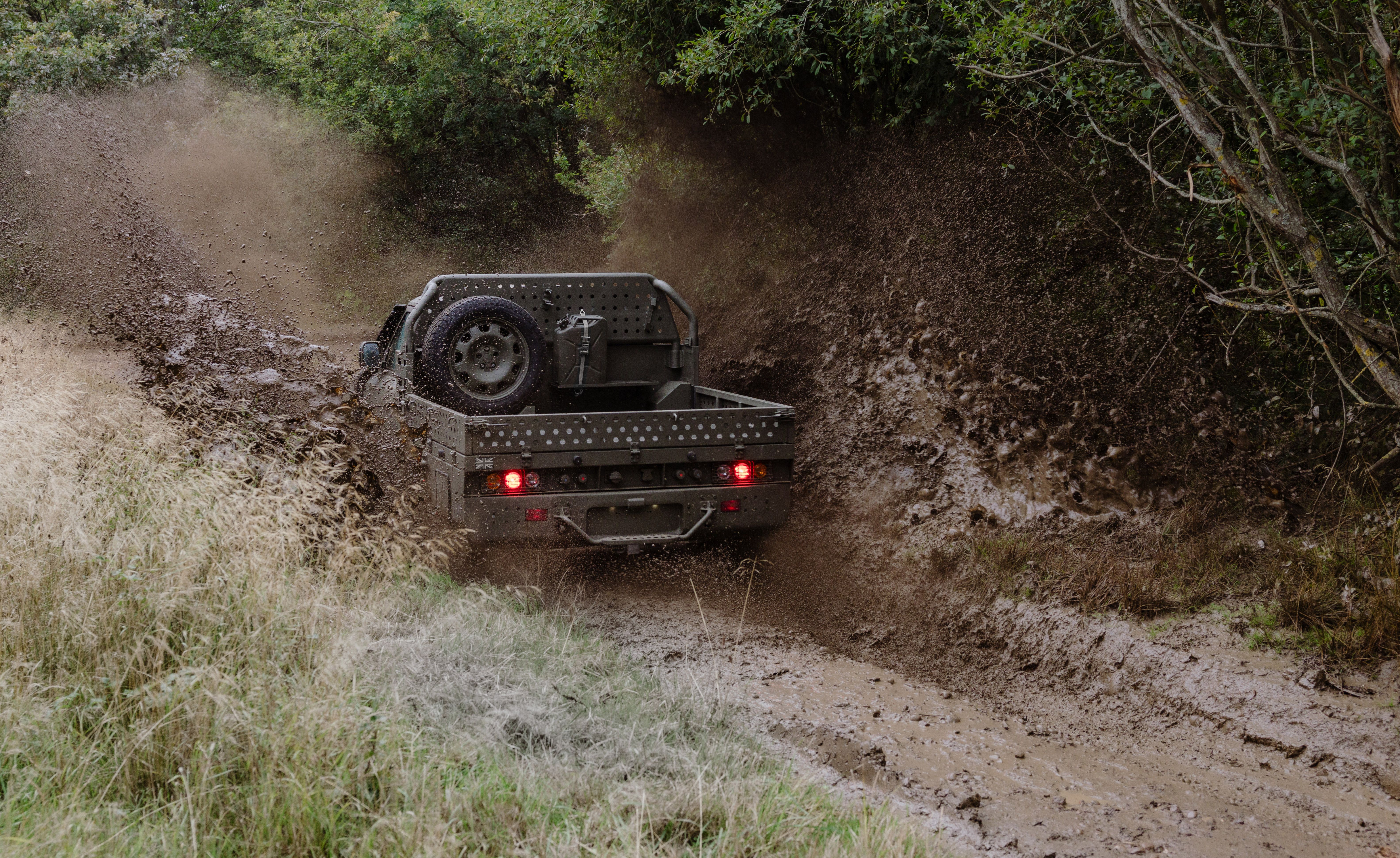 A Land Rover Defender Wolf Series II ute being driven through mud in the UK