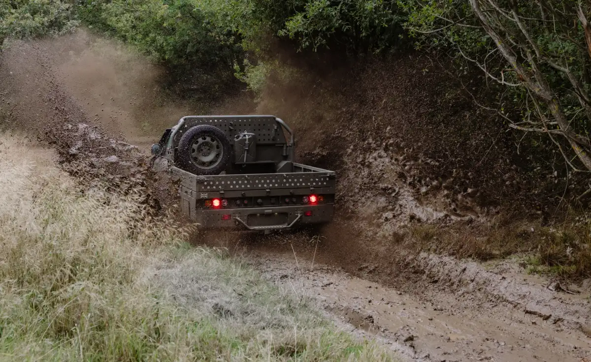 A Land Rover Defender Wolf Series II ute being driven through mud in the UK