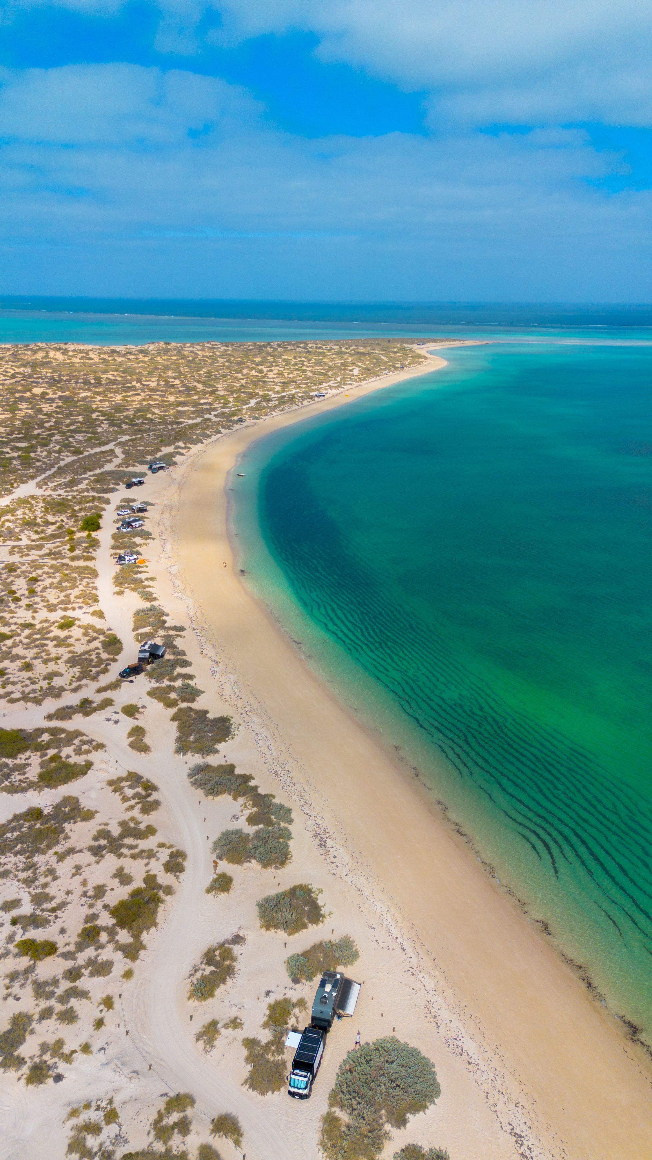 aerial shot of a beach with campers dotting the coast