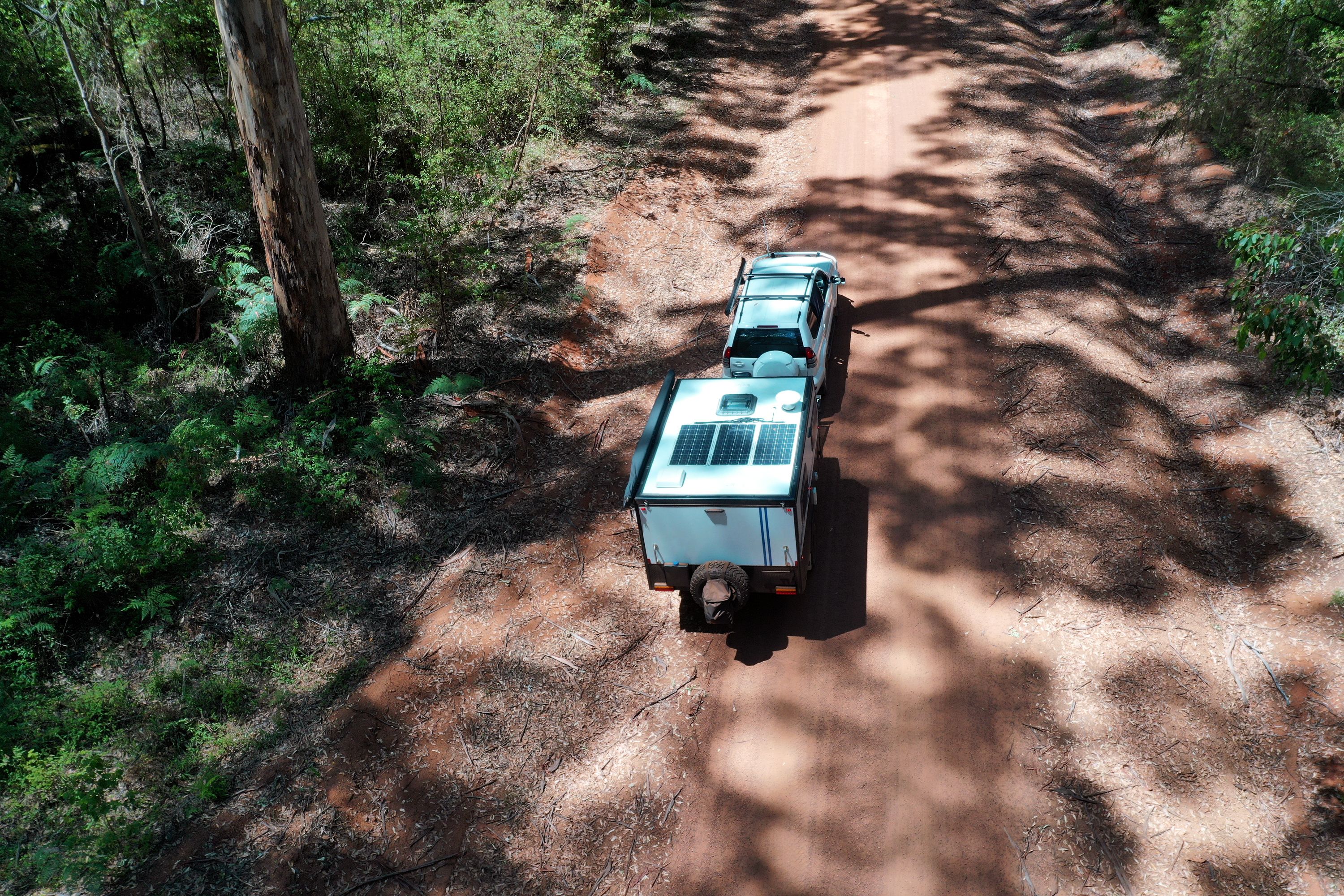 A caravan being towed through a forest dirt track