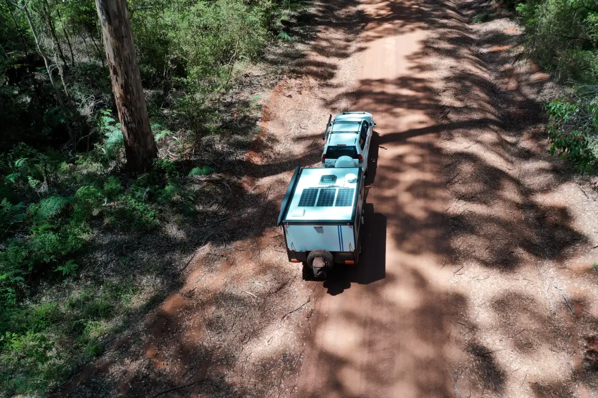 A caravan being towed through a forest dirt track