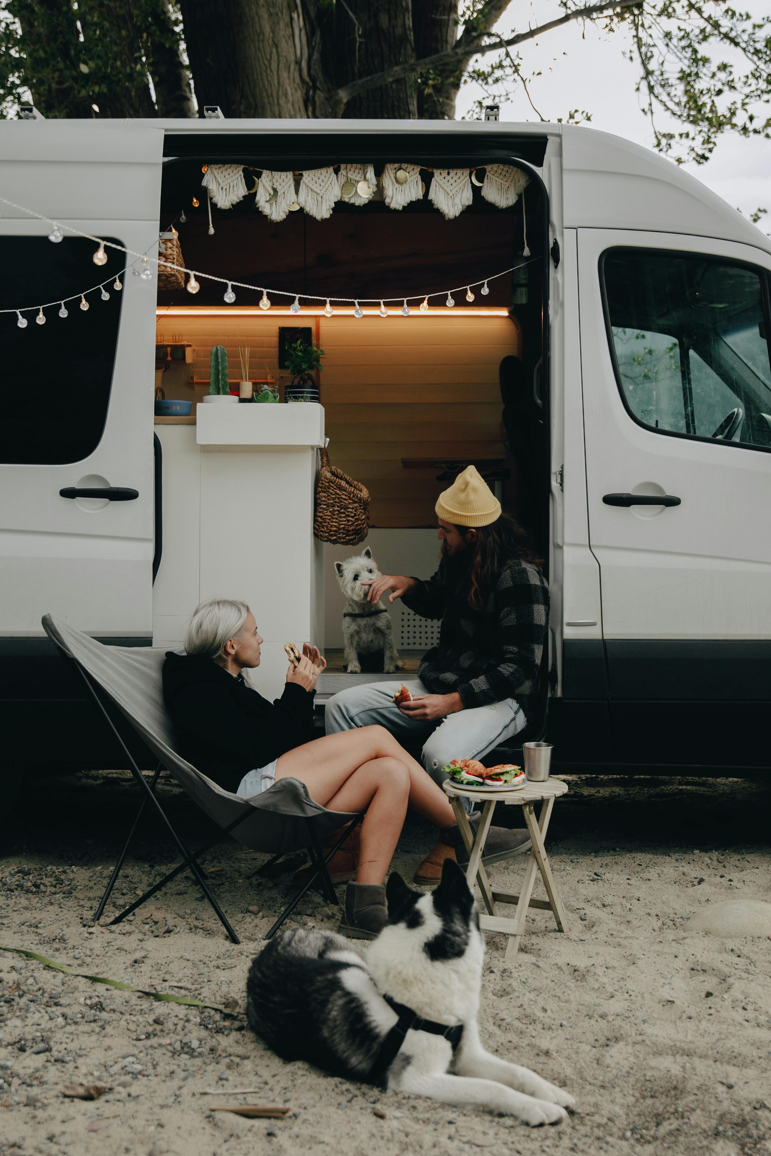 A couple and their dogs sitting outside their campervan