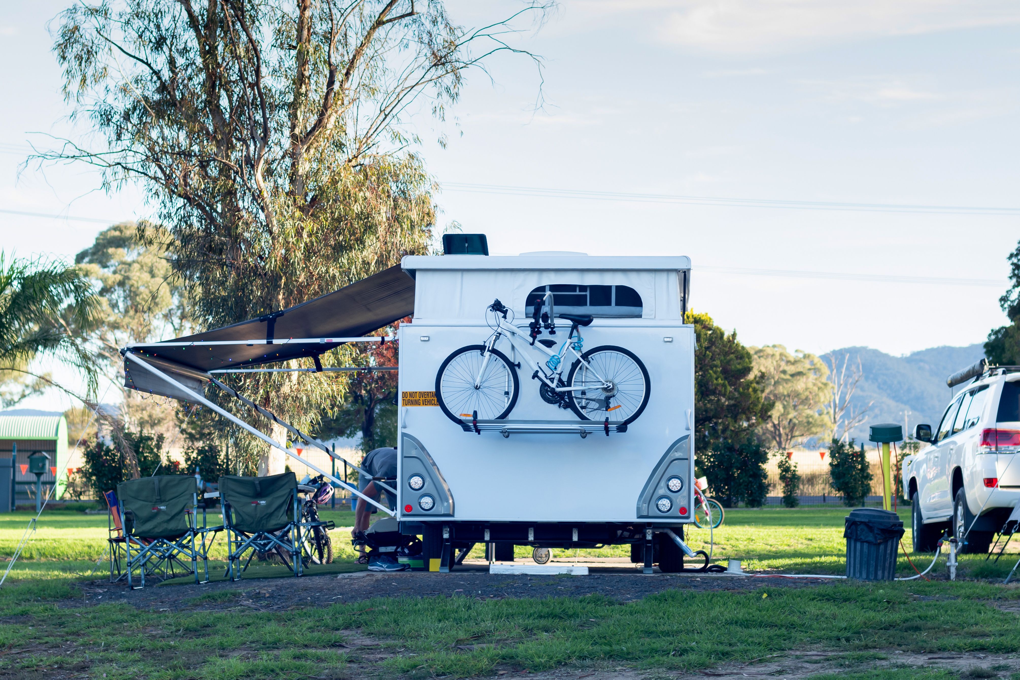 The rear of a caravan at a campsite with a bike on the back