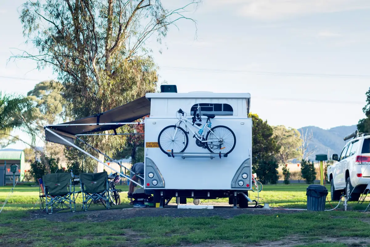 The rear of a caravan at a campsite with a bike on the back