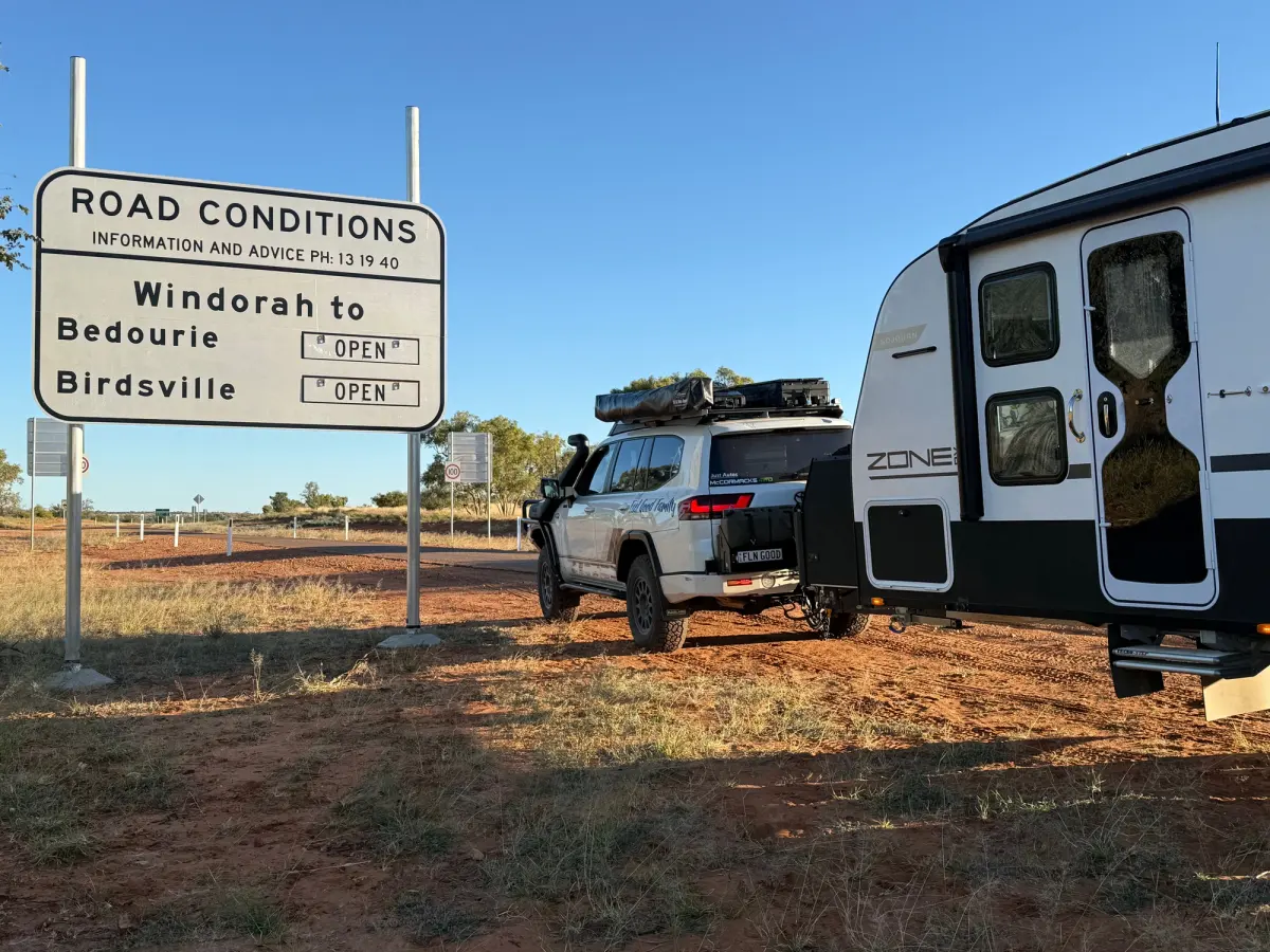 4x4 towing caravan in outback with road sign and road conditions