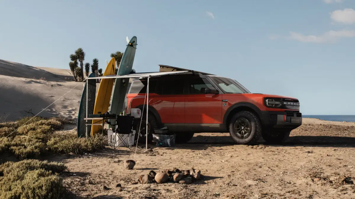 2027 Ford Bronco Basecamp on the beach by a rack of surfboards