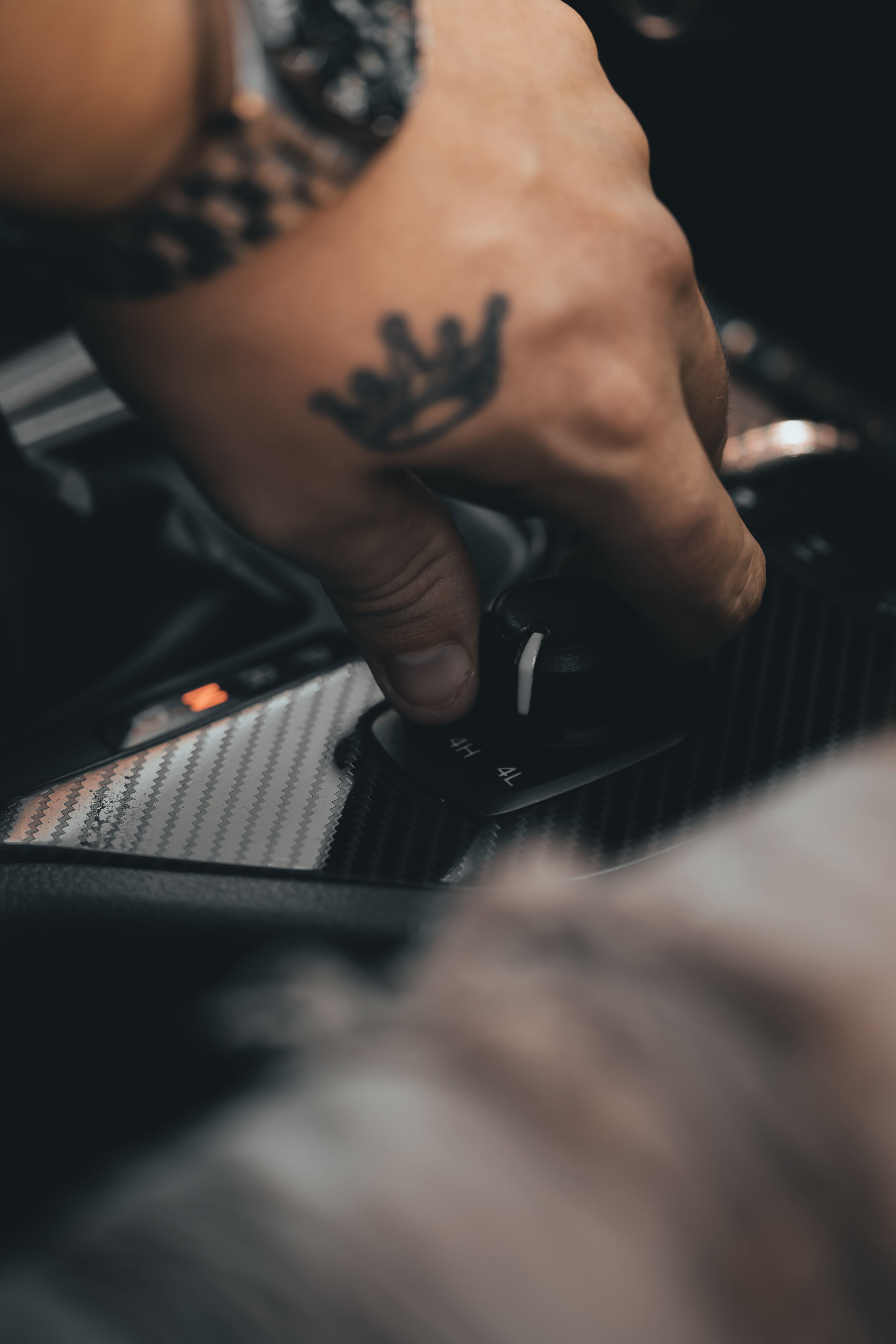 A tattooed hand of a man on a 4X4's gear stick