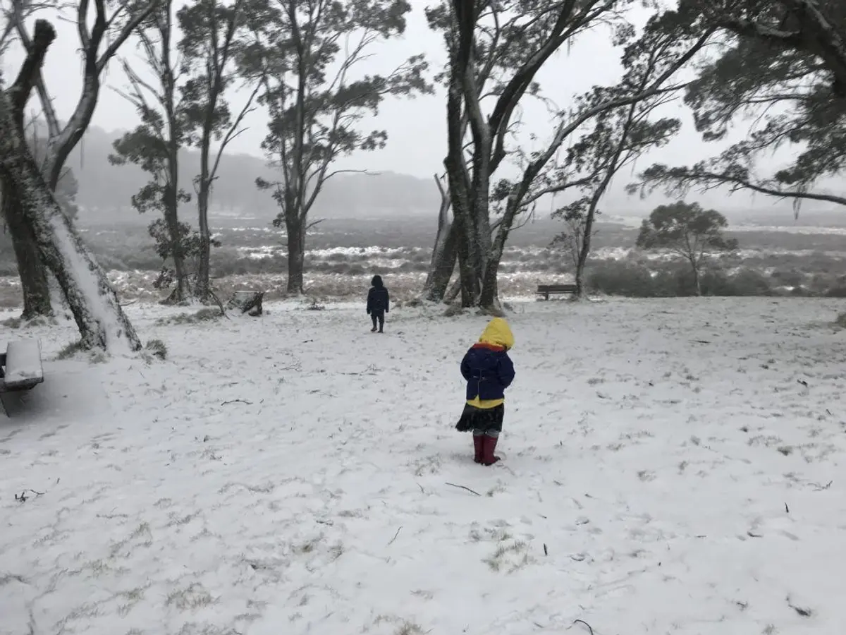 A person riding a snowboard down a snow covered field Description automatically generated