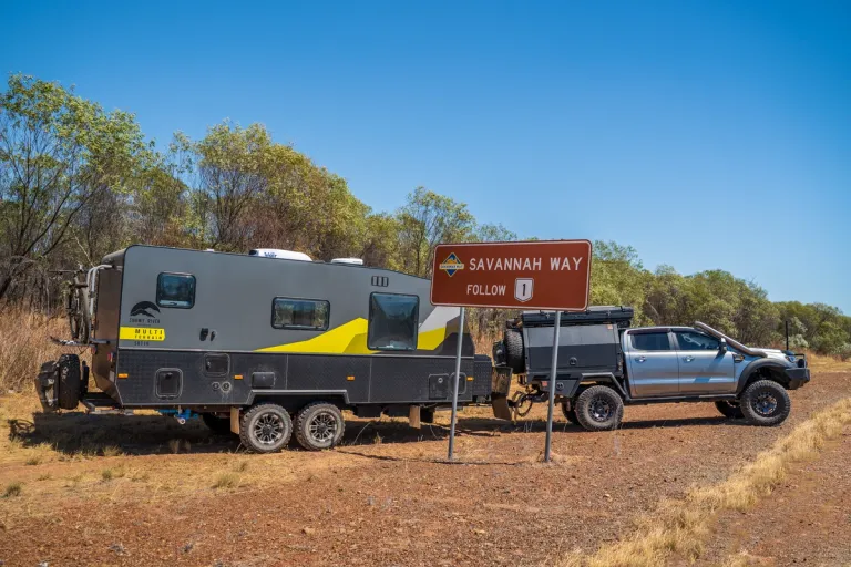 4x4 and caravan posed behind highway road sign