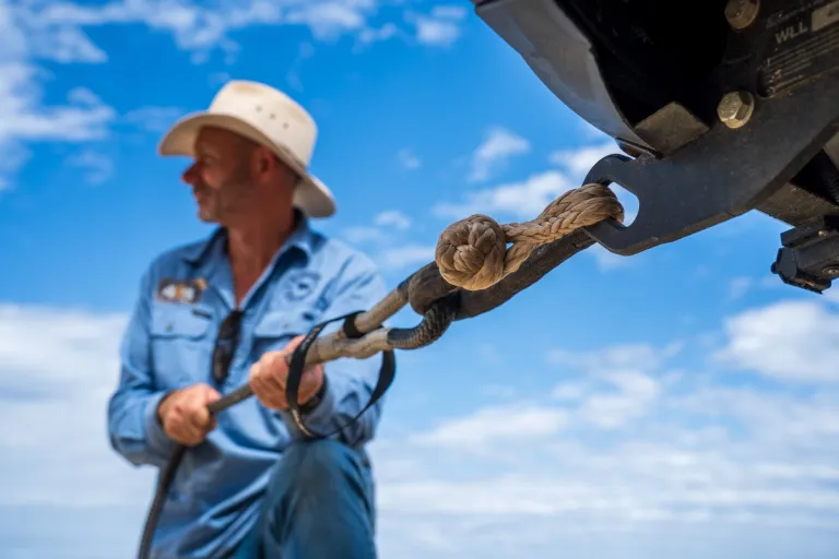 man attaching a snatch strap to a vehicle