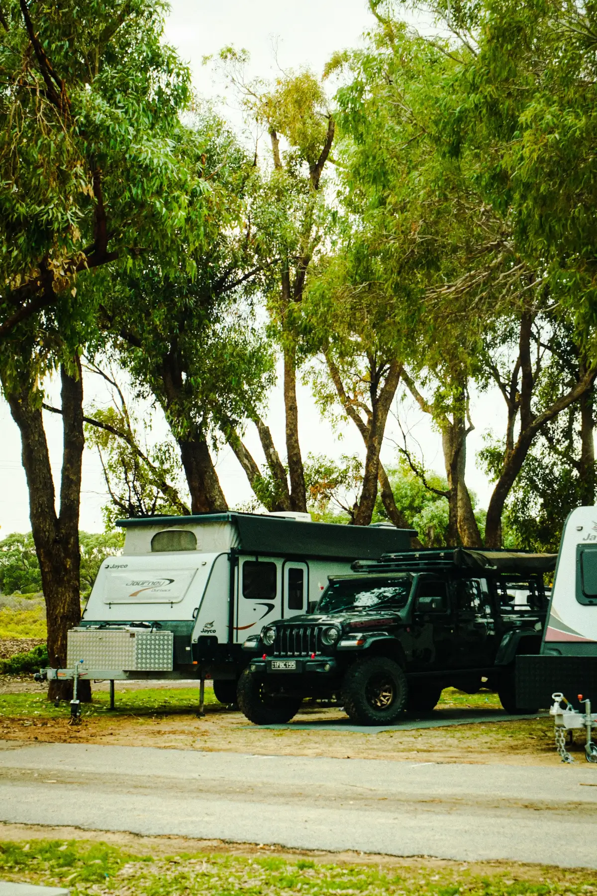 A Jeep and caravan parked in shade at a caravan park