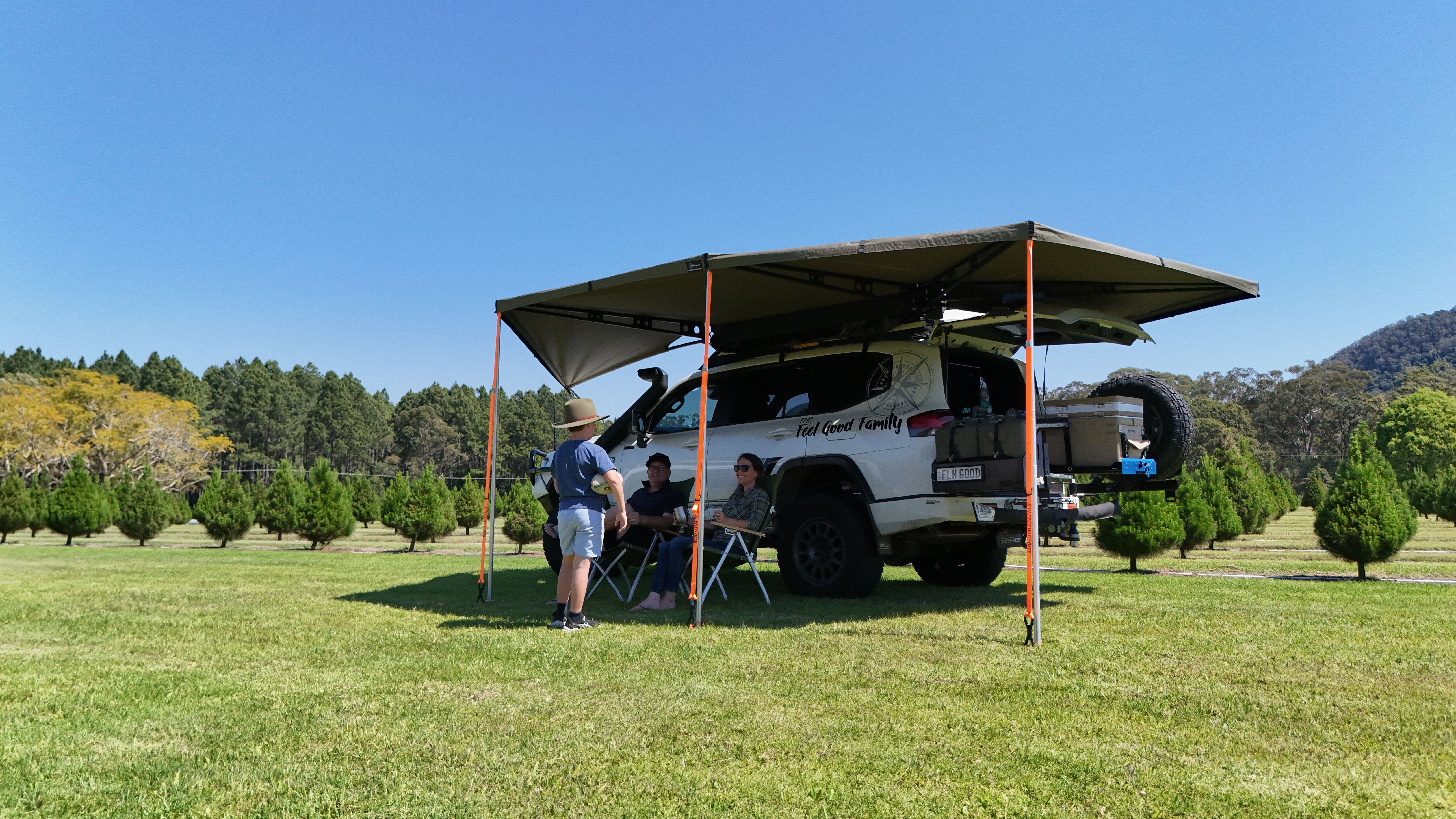 family sitting under an awning attached to a 4wd