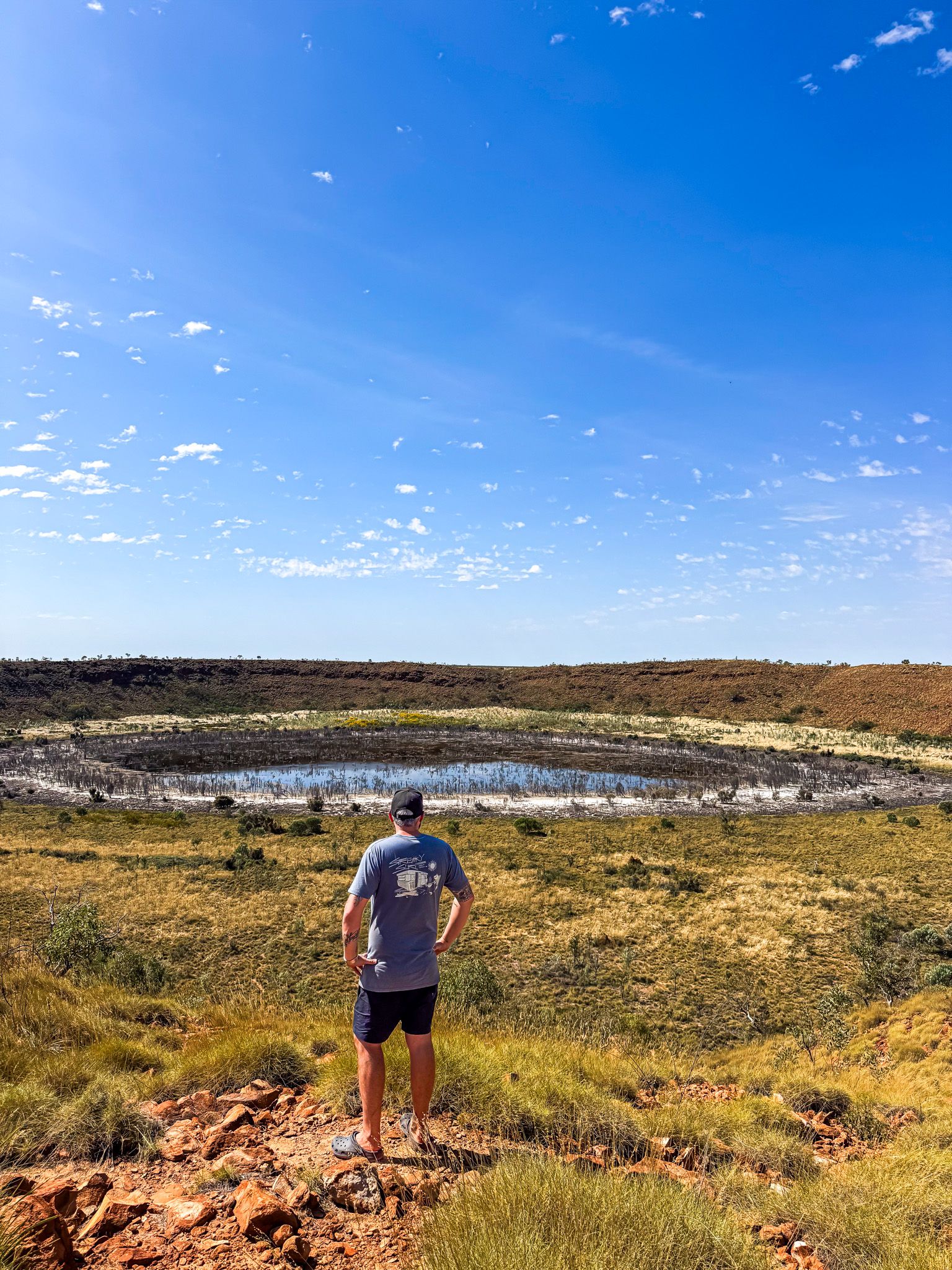 a man standing atop a ridge, looking out at a crater