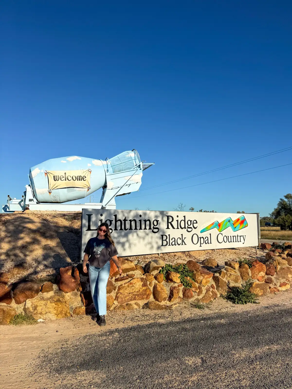 woman posing in front of a sign in the outback