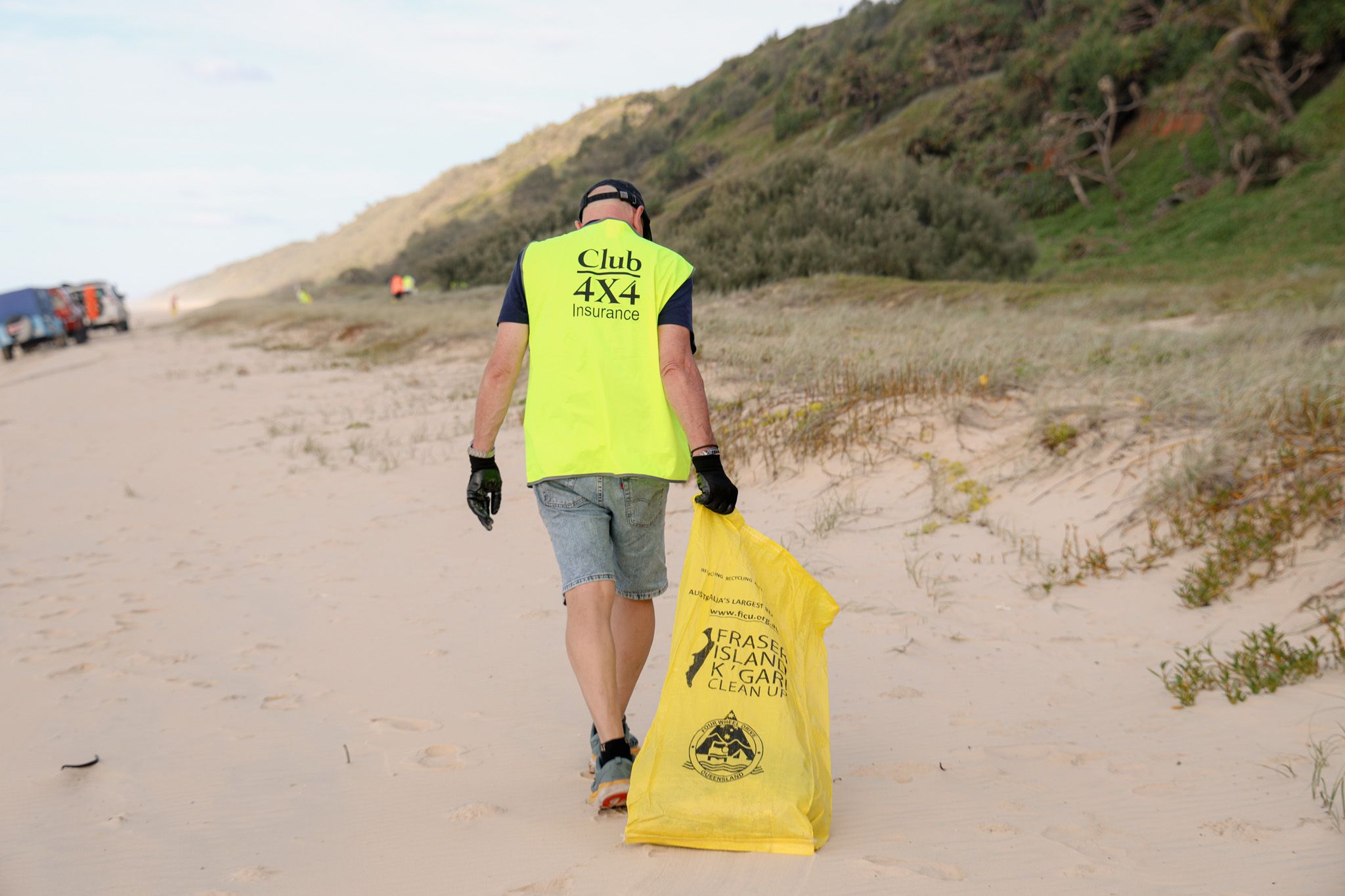 A Club 4X4 Insurance representative collecting rubbish off of a beach on K'Gari