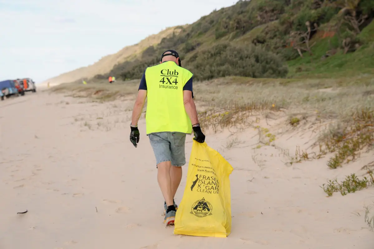 A Club 4X4 Insurance representative collecting rubbish off of a beach on K'Gari