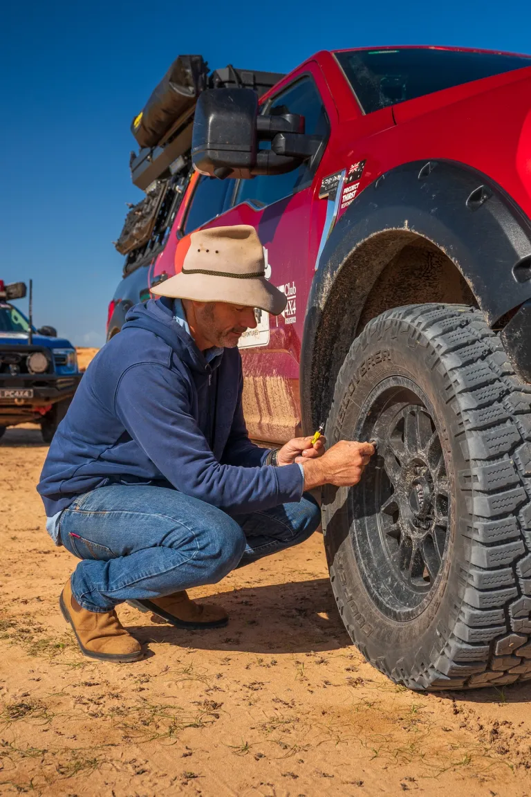 man adjusting tyre pressure on a 4x4