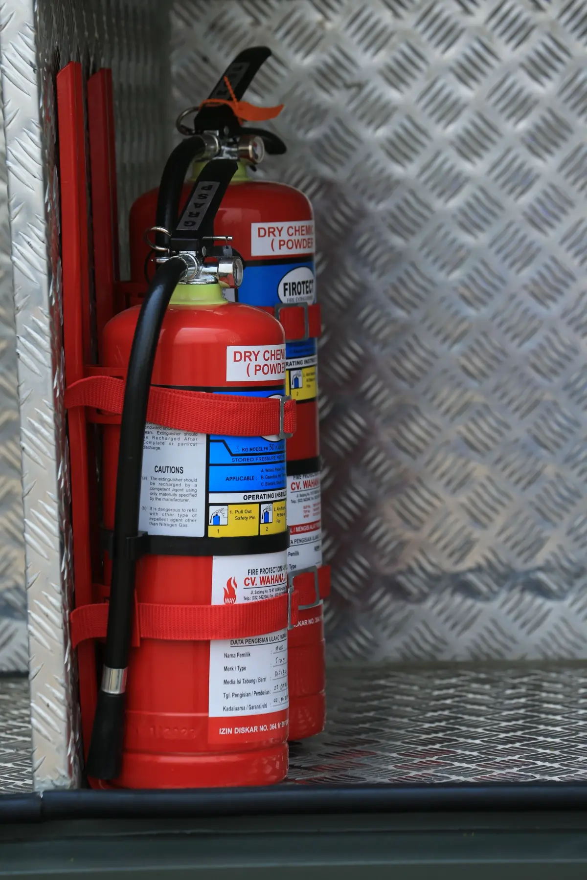2 fire extinguishers in a metal compartment on a vehicle
