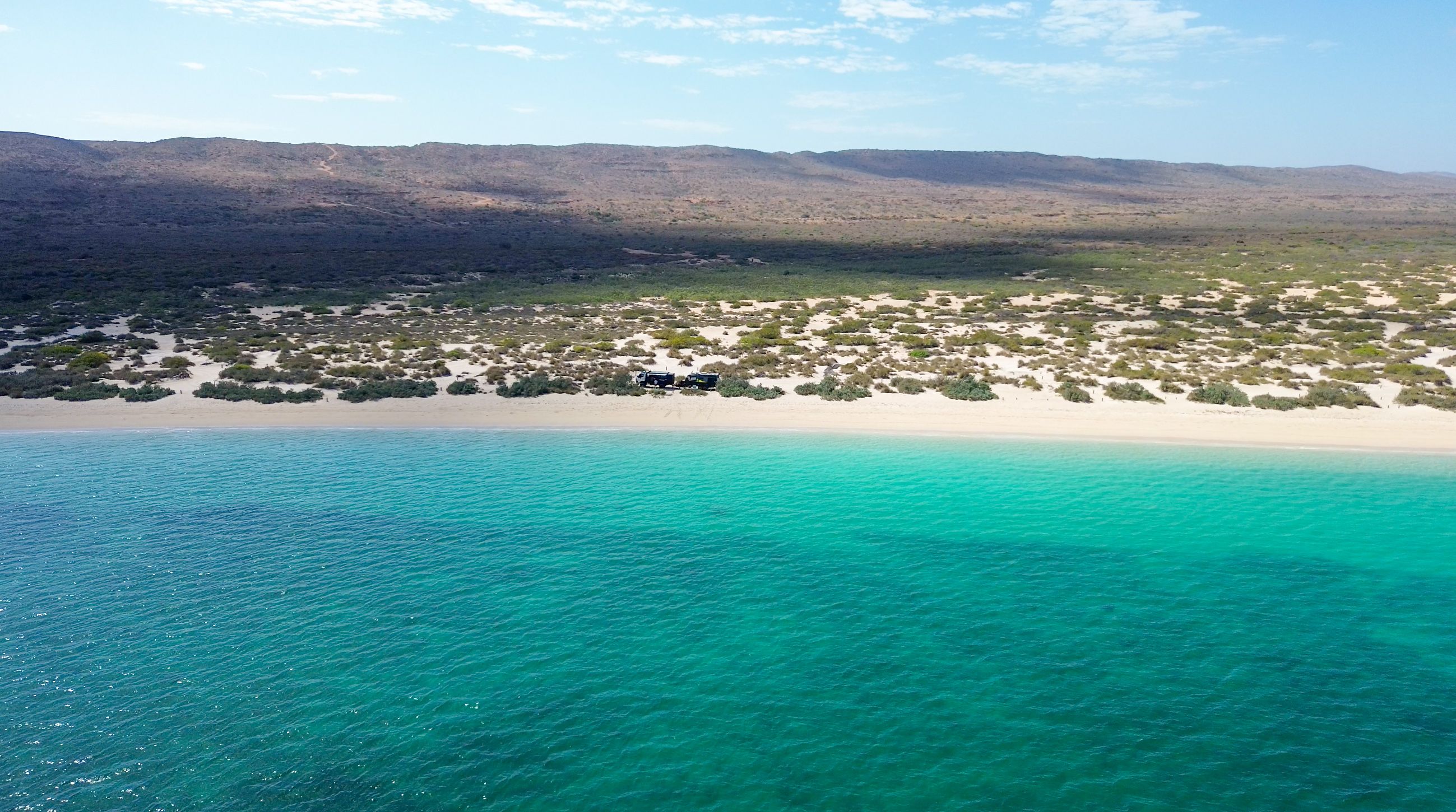 An aerial view of a beach with turquoise water