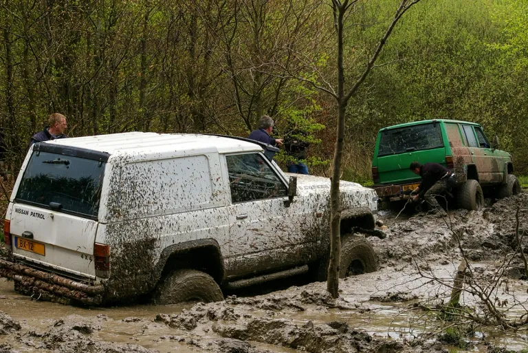 two nissan patrol 4x4 driving through mud