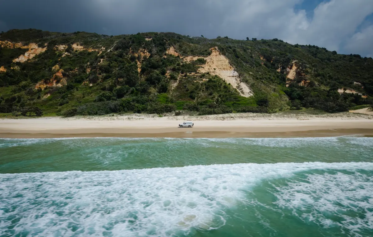 a 4X4 on Teewah Beach, shot from a drone over the ocean