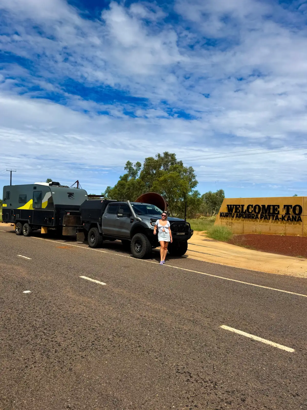 woman standing in front of a 4x4 in front of a sign in outback