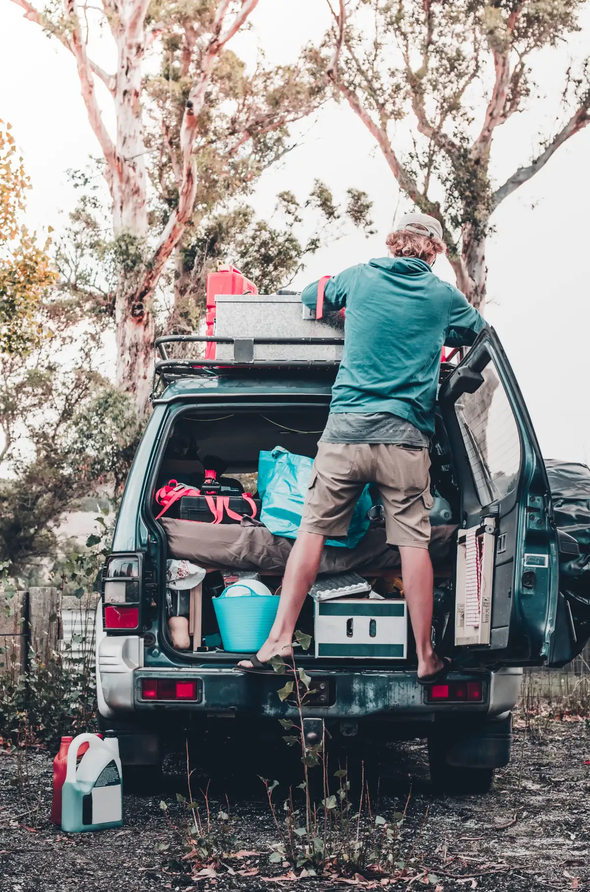 A blonde backpacker and solo traveler checks his 4X4 before a roadtrip