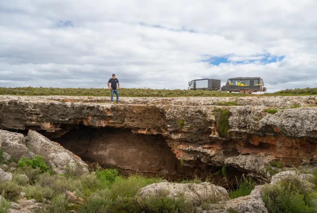 Man standing over a sinkhole with a 4X4 and caravan in the background