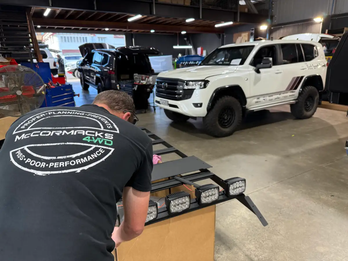 Man in a workshop installing driving lights to a 4WD