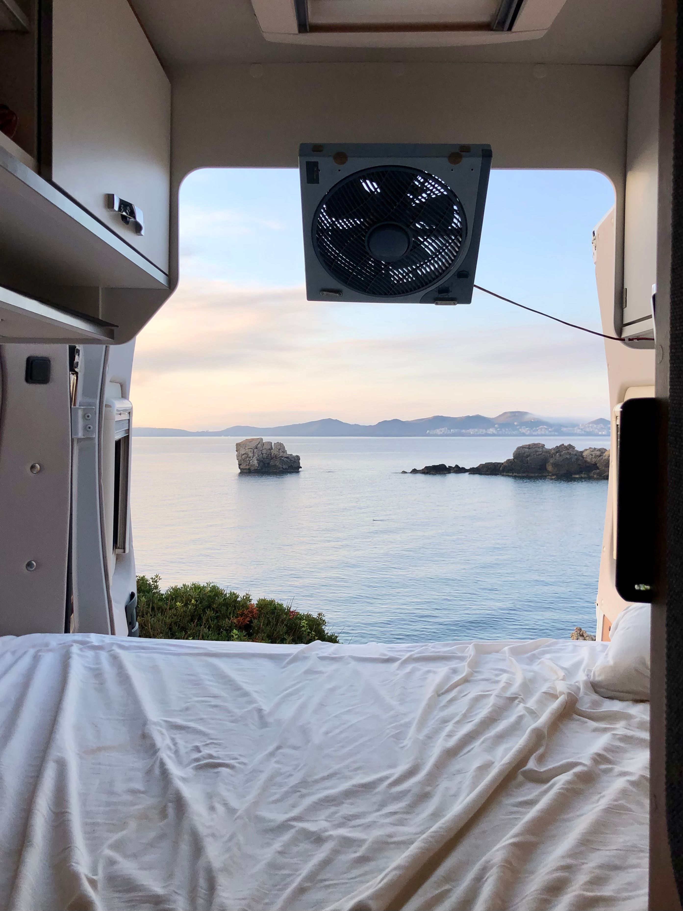 A portable fan on the roof of a campervan looking out over the ocean