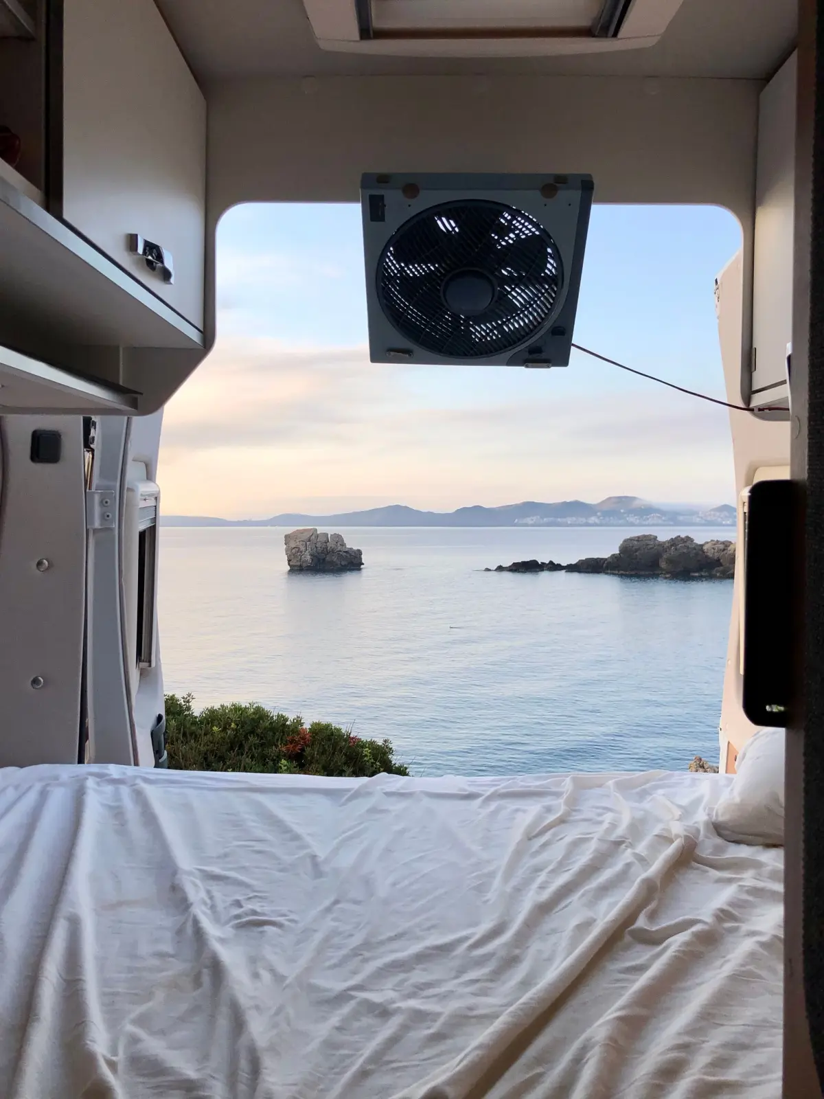A portable fan on the roof of a campervan looking out over the ocean