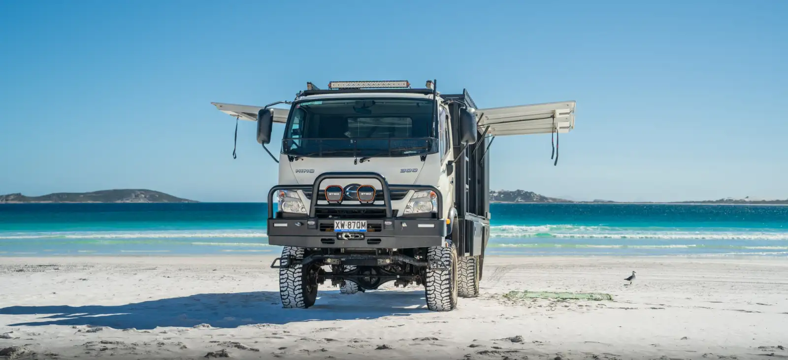 Hino 300 4WD light truck on beach with sides of canopy open