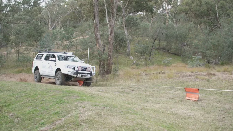 A car parked on pavement near a forest Description automatically generated