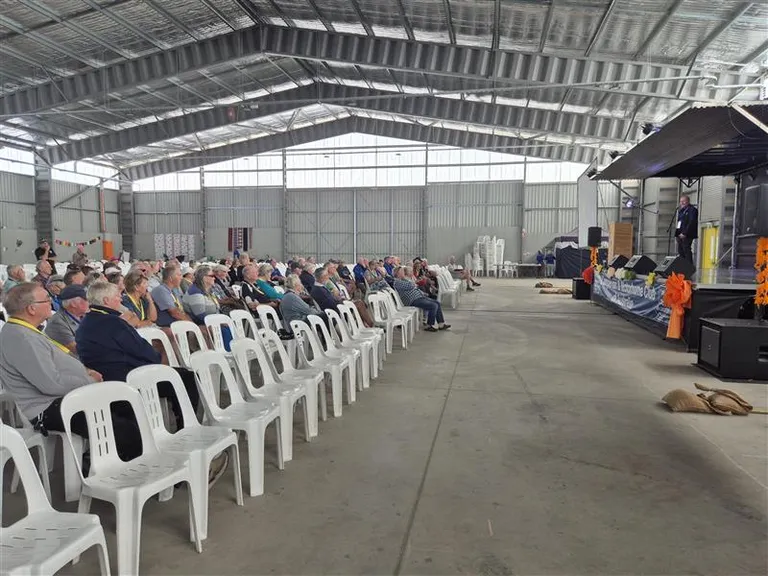 man doing speech in front of crown in a shed