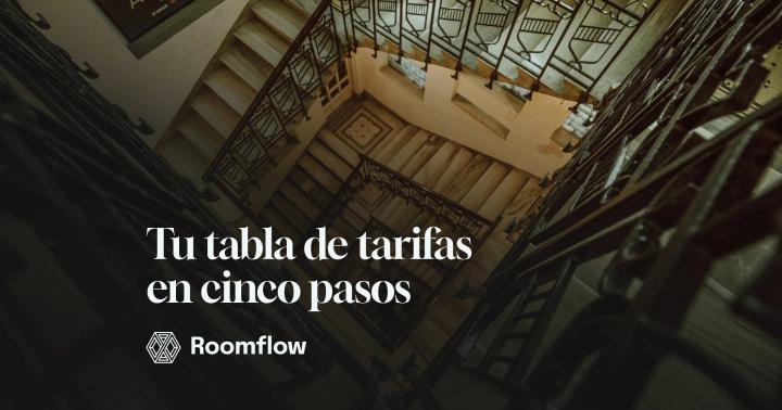 Escalera de un edificio histórico vista desde arriba, con barandillas de hierro y peldaños de madera.