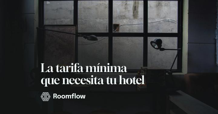 Escritorio con máquina de escribir y flexo junto a un ventanal de cuadrícula en penumbra.