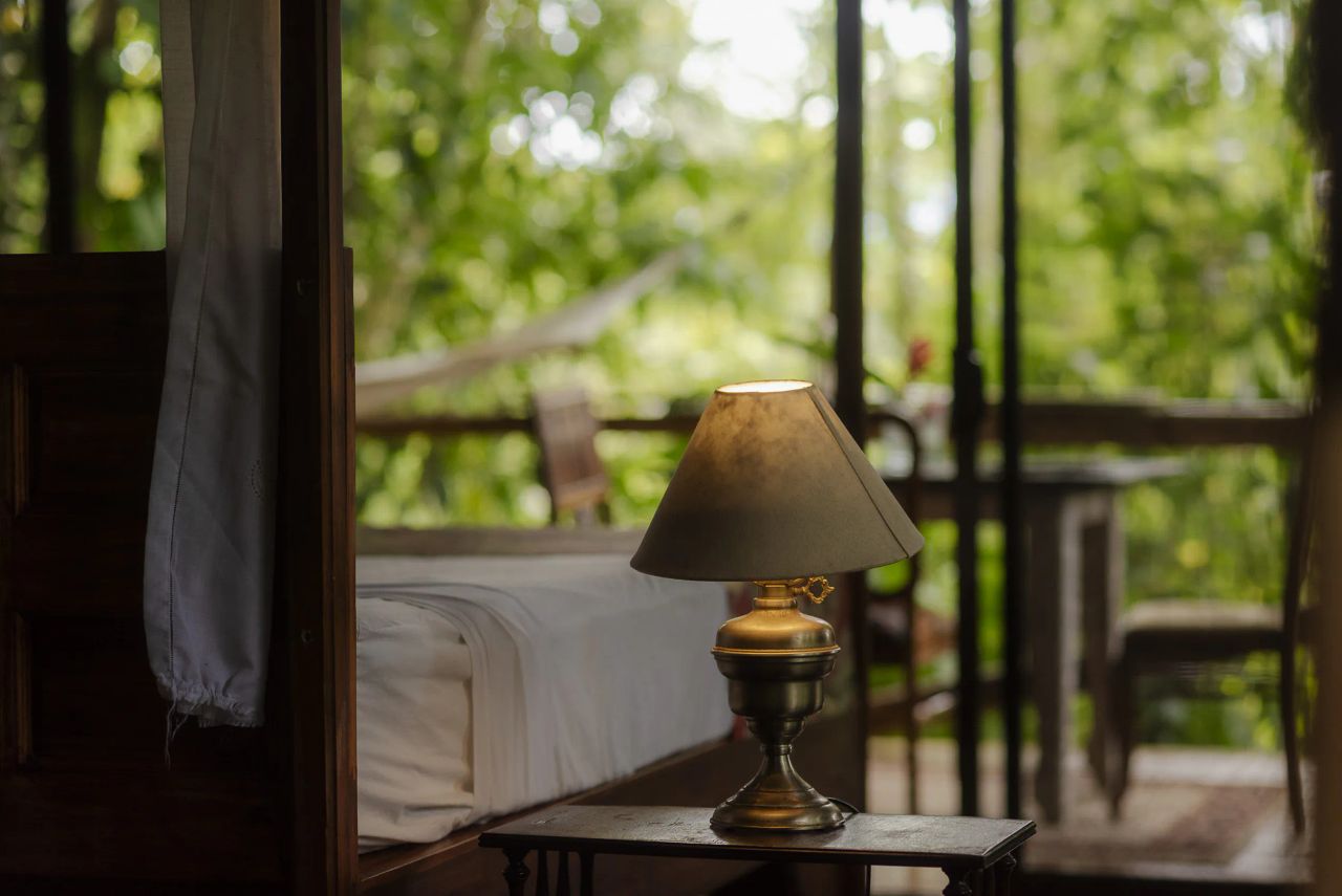 Tienda de glamping de Colina Secreta con la lámpara encendida y la selva de Puerto Viejo al fondo