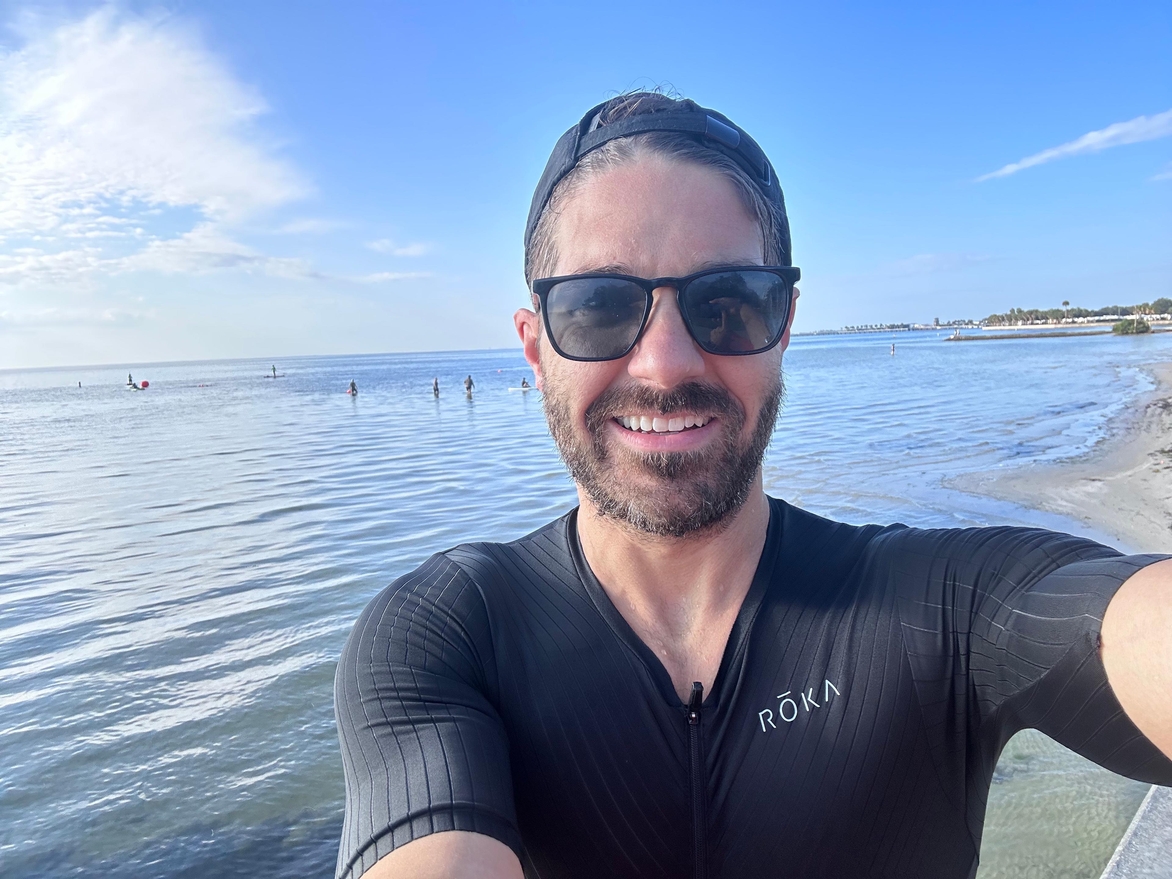 Pat Cahill standing and in front of the Gulf of Mexico after an open water swim